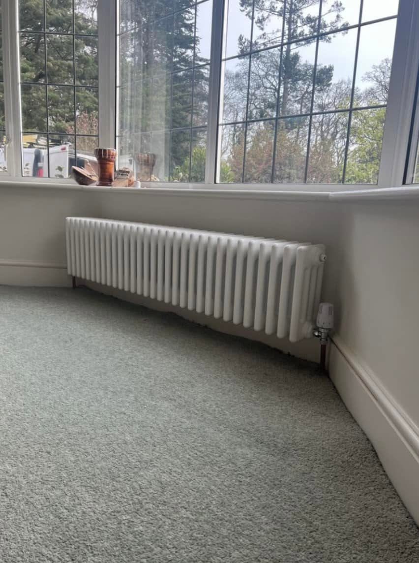 White column radiator fitted under a bay window in Exeter