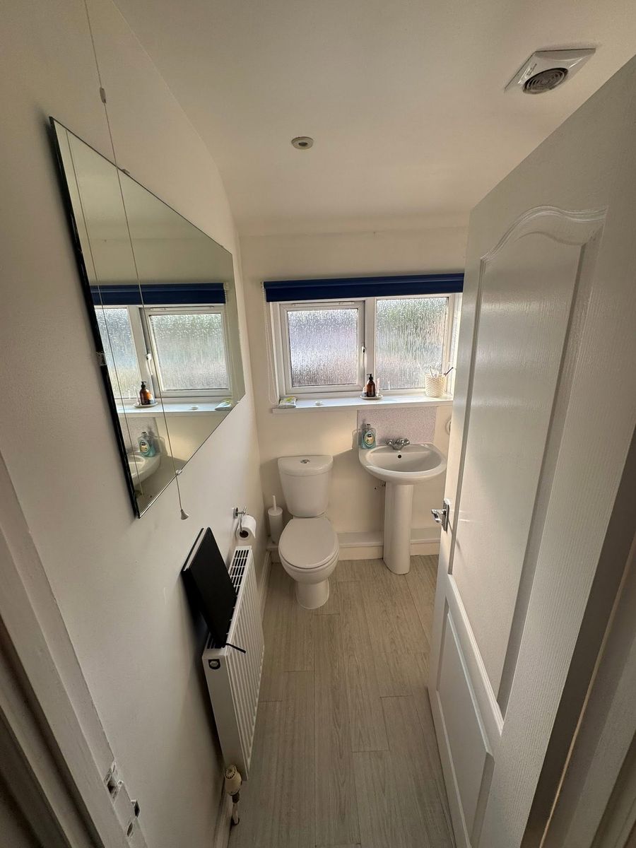 Bath with black-framed folding shower screen and grey tiling