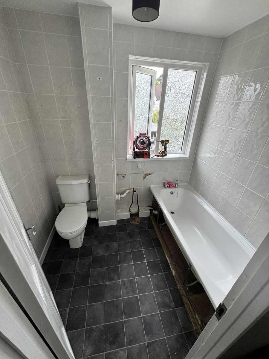 Bathroom before — old bath and tired tiling